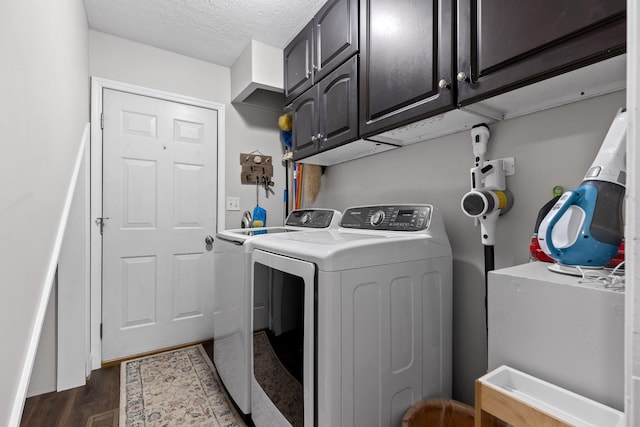 laundry area with a textured ceiling, dark wood-type flooring, cabinets, and independent washer and dryer