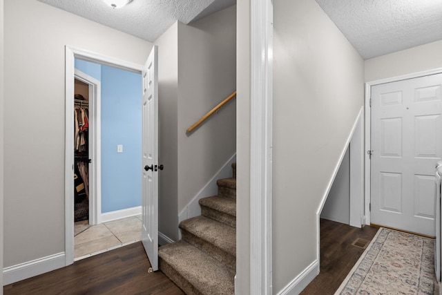 stairs with a textured ceiling and hardwood / wood-style floors