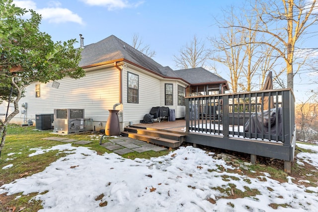 snow covered rear of property featuring a deck and central AC