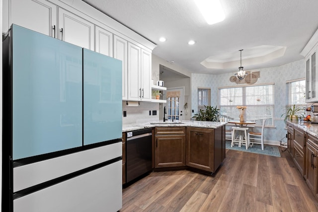 kitchen featuring kitchen peninsula, dishwasher, a tray ceiling, dark hardwood / wood-style flooring, and white cabinetry