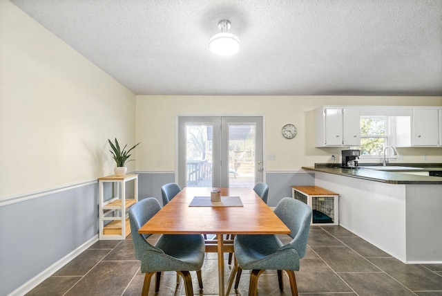 dining area featuring sink, dark tile patterned flooring, a textured ceiling, and plenty of natural light