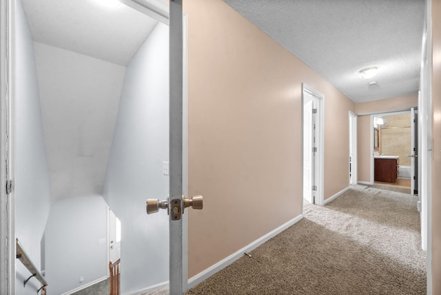 hallway with a textured ceiling and carpet