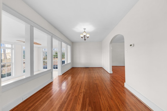 empty room featuring hardwood / wood-style flooring and ceiling fan with notable chandelier