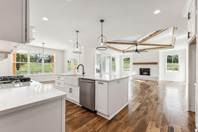 kitchen with stainless steel appliances, sink, white cabinetry, pendant lighting, and a kitchen island with sink