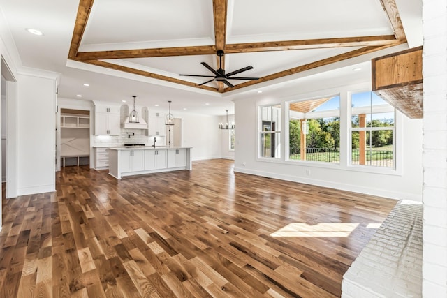 unfurnished living room with sink, dark wood-type flooring, ceiling fan, and ornamental molding