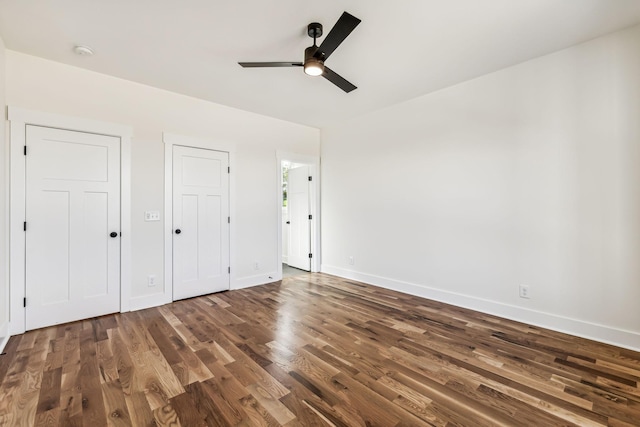 unfurnished bedroom featuring wood-type flooring, two closets, and ceiling fan