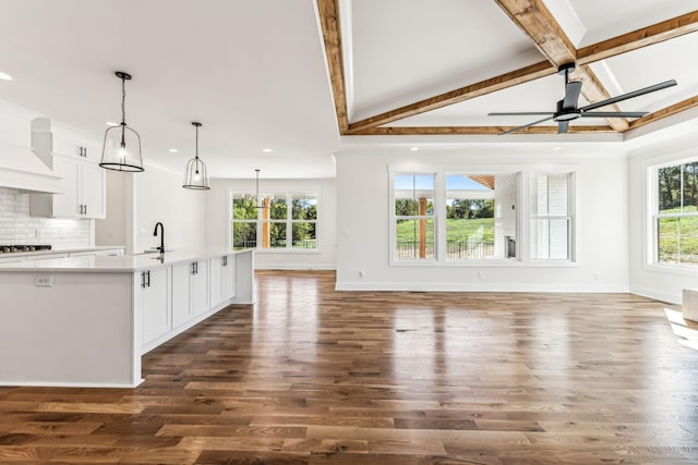 unfurnished living room with sink, ceiling fan, vaulted ceiling with beams, and dark hardwood / wood-style floors