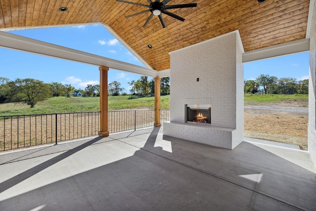 view of patio / terrace with a rural view, ceiling fan, and an outdoor brick fireplace