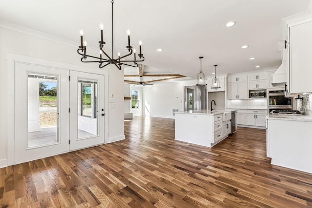 kitchen with decorative light fixtures, a center island with sink, white cabinetry, ceiling fan with notable chandelier, and appliances with stainless steel finishes