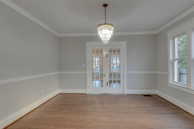 unfurnished dining area with ornamental molding, french doors, a notable chandelier, and hardwood / wood-style floors