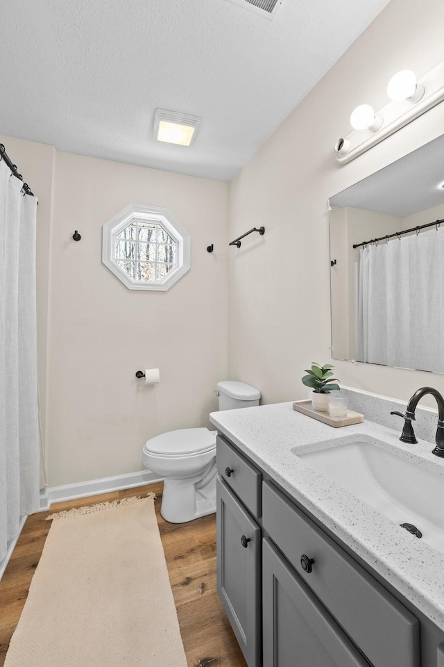 bathroom featuring toilet, vanity, a textured ceiling, and hardwood / wood-style floors