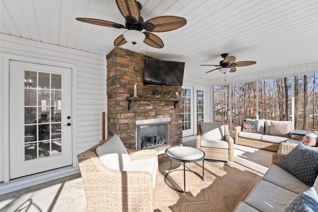 sunroom / solarium with ceiling fan and an outdoor stone fireplace