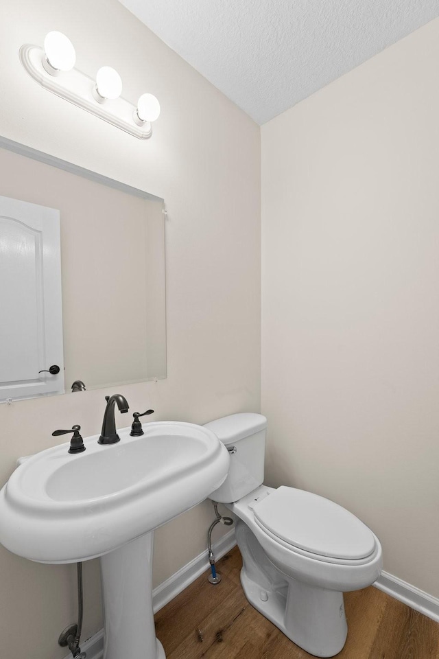 bathroom with toilet, a textured ceiling, and hardwood / wood-style floors