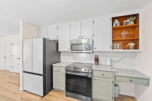 kitchen with decorative backsplash, light stone counters, light hardwood / wood-style flooring, and appliances with stainless steel finishes