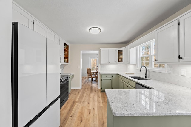 kitchen with range with electric stovetop, refrigerator, light stone counters, white cabinets, and sink