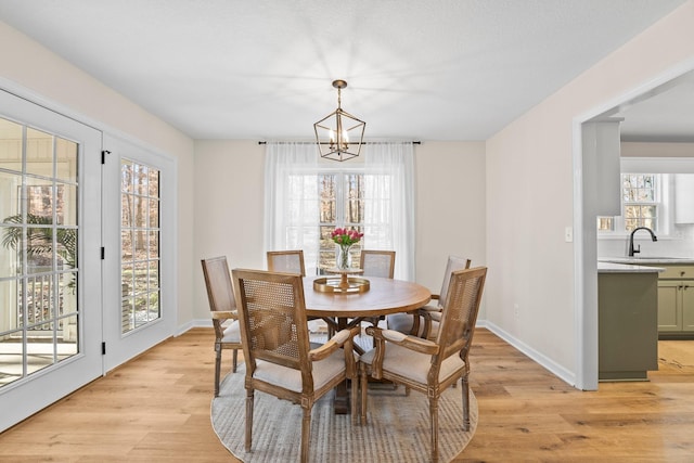 dining room with light hardwood / wood-style floors, a chandelier, and sink