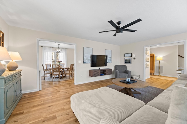 living room featuring light wood-type flooring and ceiling fan with notable chandelier