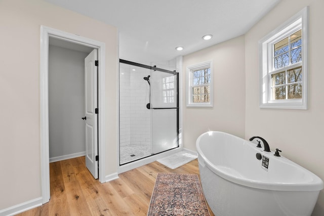 bathroom with shower with separate bathtub and wood-type flooring