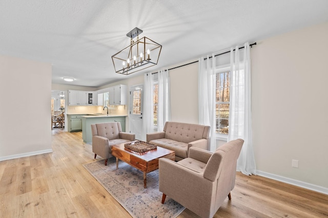 living room with sink, an inviting chandelier, and light hardwood / wood-style flooring