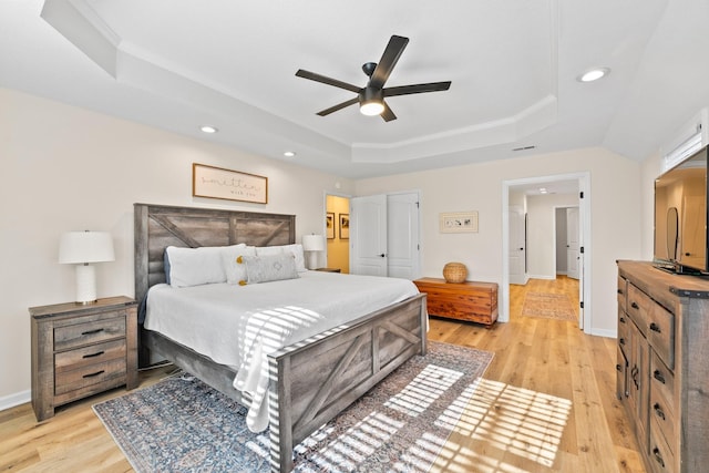 bedroom with ornamental molding, a raised ceiling, ceiling fan, and light wood-type flooring