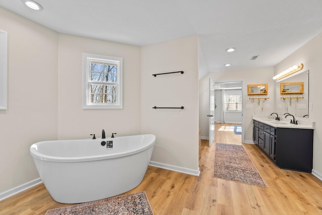 bathroom with a bathing tub, hardwood / wood-style flooring, and vanity