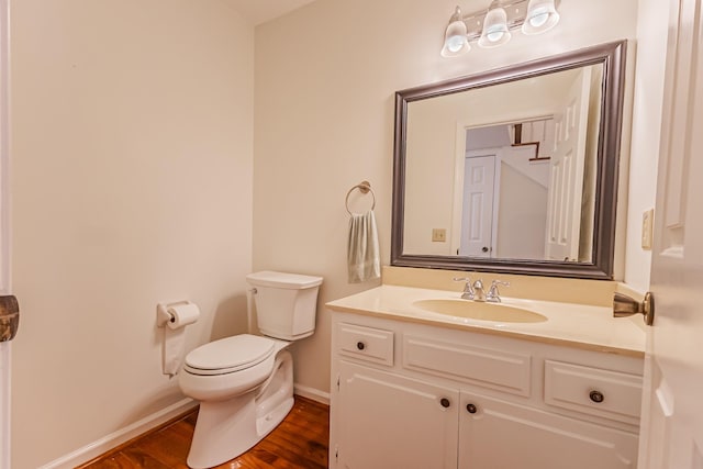 bathroom with toilet, hardwood / wood-style flooring, and vanity