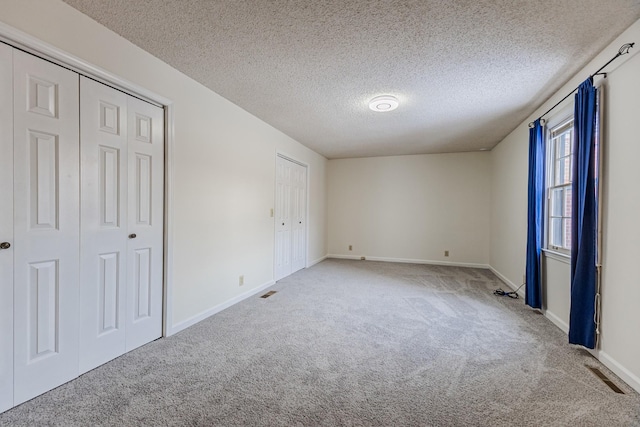 unfurnished bedroom featuring a textured ceiling and light carpet