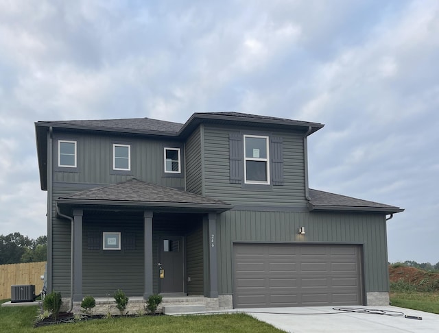 view of front property with a front yard, central AC unit, and a garage