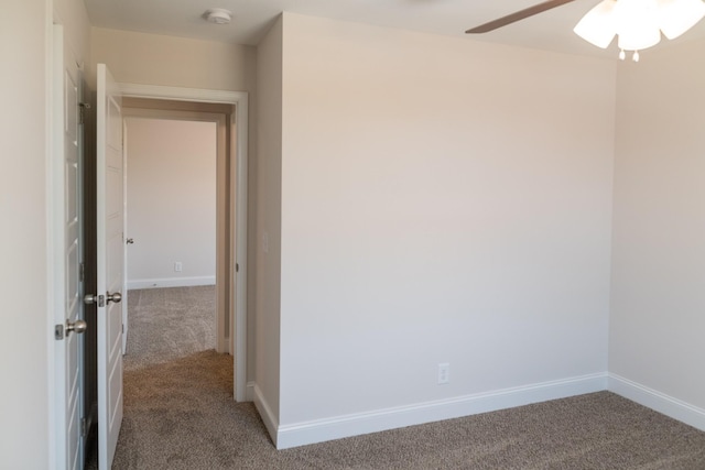 carpeted spare room featuring a ceiling fan and baseboards