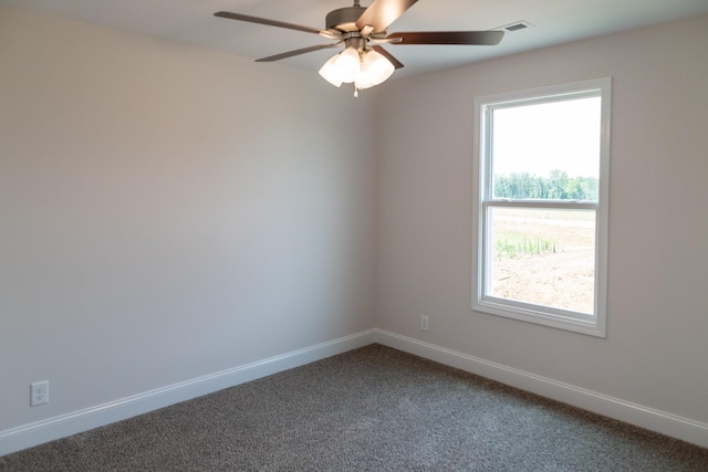 spare room featuring visible vents, baseboards, dark colored carpet, and a ceiling fan