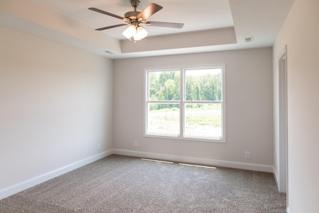 unfurnished room featuring ceiling fan, carpet, a raised ceiling, and baseboards