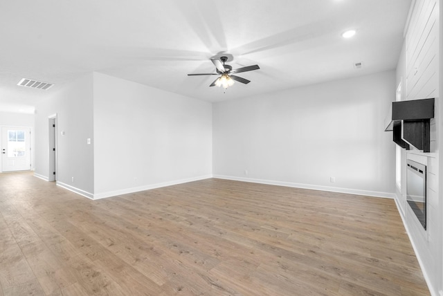 unfurnished living room with ceiling fan, a fireplace, and light wood-type flooring