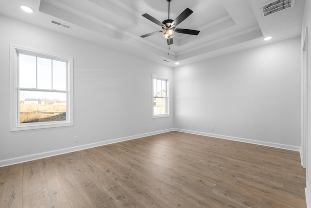 unfurnished room with hardwood / wood-style flooring, ceiling fan, ornamental molding, and a raised ceiling