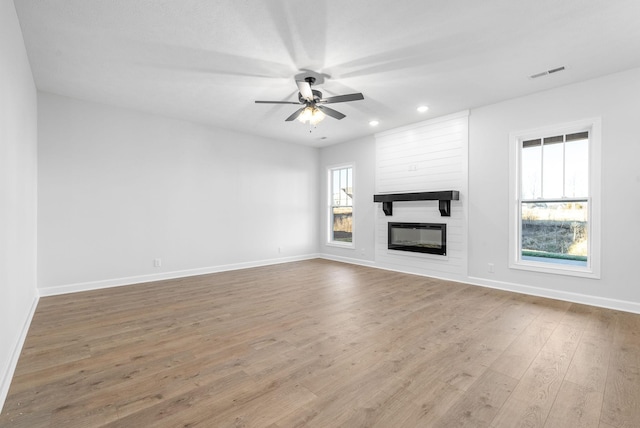 unfurnished living room with ceiling fan, a fireplace, and hardwood / wood-style flooring