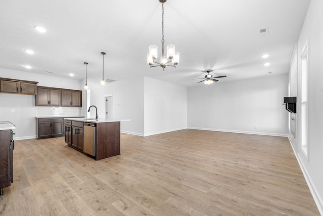 kitchen with a kitchen island with sink, sink, stainless steel dishwasher, and hanging light fixtures