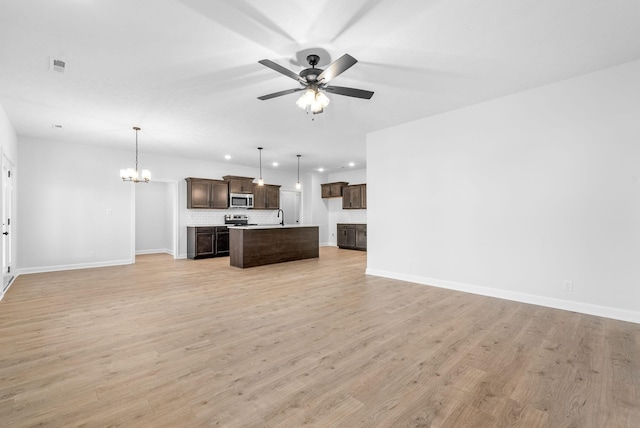 unfurnished living room with sink, ceiling fan with notable chandelier, and light wood-type flooring