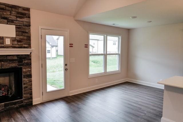 doorway to outside with a fireplace, baseboards, dark wood-type flooring, and a wealth of natural light