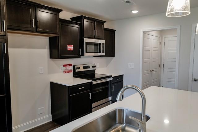 kitchen with visible vents, baseboards, stainless steel appliances, light countertops, and a sink