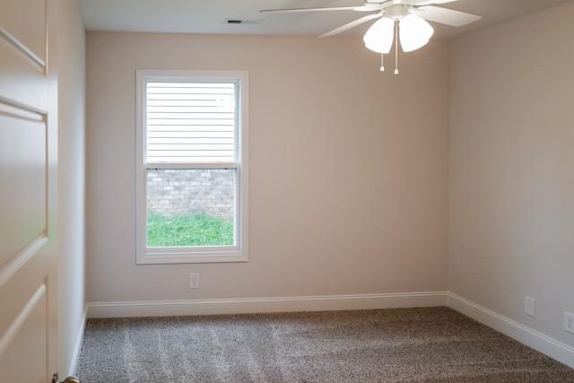 carpeted empty room featuring ceiling fan and baseboards