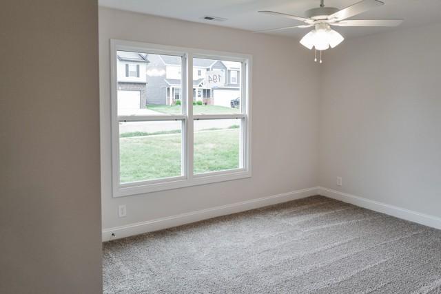 carpeted empty room with visible vents, ceiling fan, and baseboards