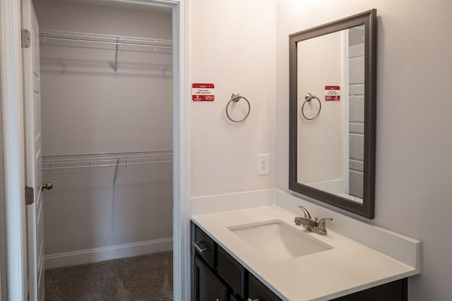 bathroom featuring a spacious closet, vanity, and baseboards