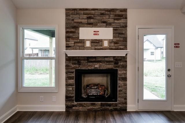 unfurnished living room with a fireplace, baseboards, and wood finished floors