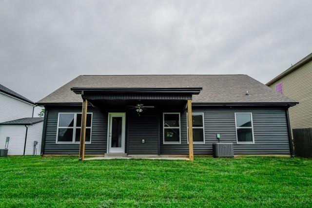 rear view of house with roof with shingles, ceiling fan, a lawn, and central AC unit