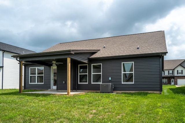 rear view of house featuring a lawn, a ceiling fan, a patio, roof with shingles, and central AC