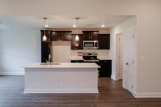 kitchen with light countertops, appliances with stainless steel finishes, dark wood-type flooring, and a sink