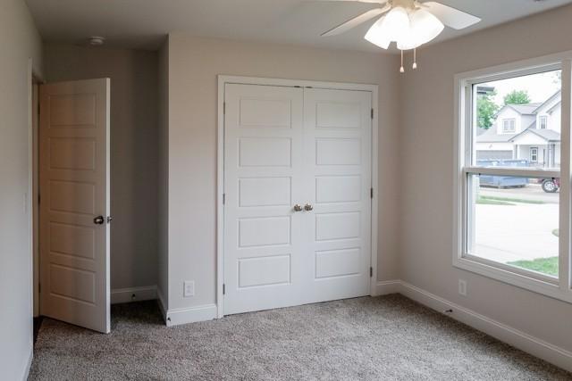 unfurnished bedroom featuring a closet, multiple windows, baseboards, and carpet flooring