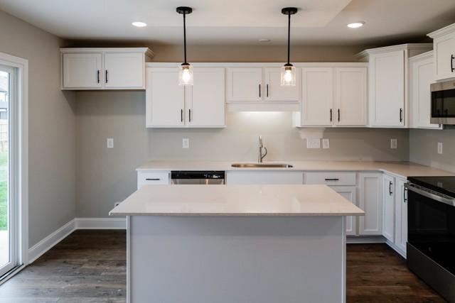 kitchen with stainless steel appliances, white cabinets, hanging light fixtures, and sink