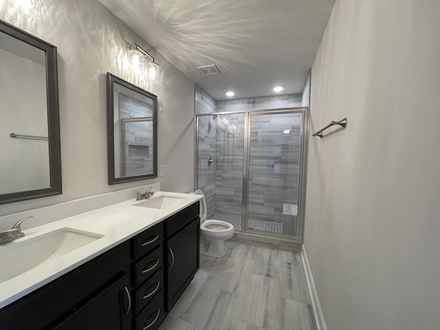 full bath with double vanity, a sink, toilet, and a shower stall