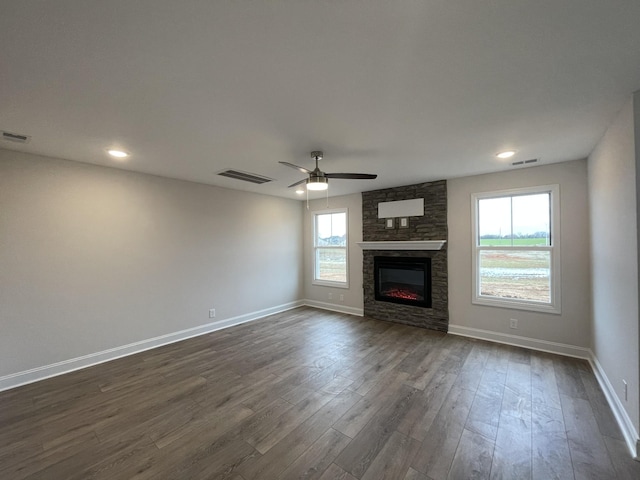 unfurnished living room featuring dark wood-style floors, visible vents, a fireplace, and baseboards