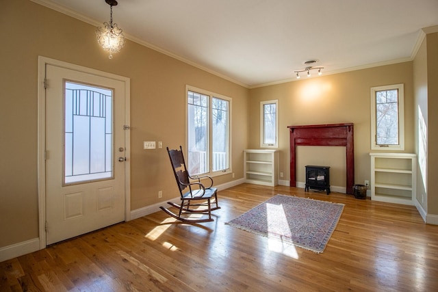 entryway with crown molding, a chandelier, light hardwood / wood-style flooring, and a wood stove